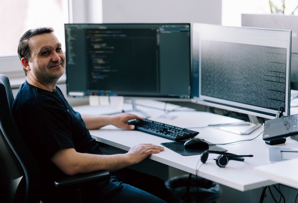 Ein Mann arbeitet an einem Schreibtisch, ausgestattet mit zwei Computerbildschirmen.