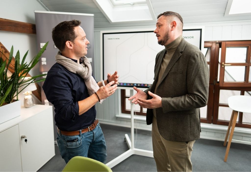 Zwei Männer führen ein Gespräch in einem Büro.