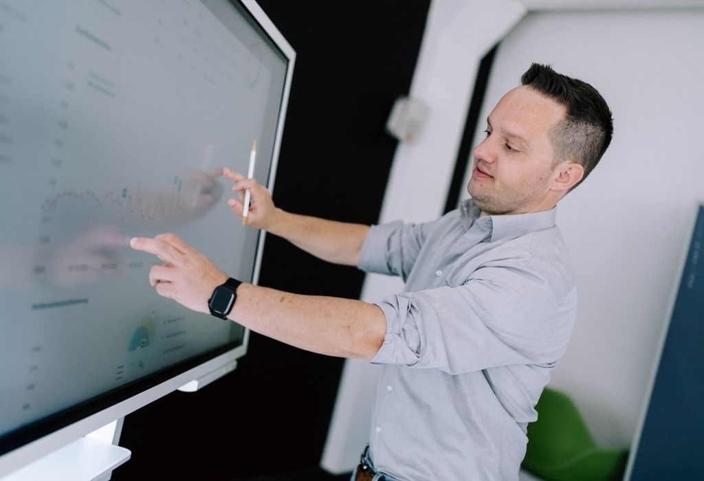 Ein Mann interagiert mit einem großen Bildschirm, um wichtige Daten zur Webentwicklung zu analysieren.
